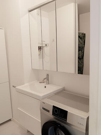 Bathroom with sink, storage cabinets, and washing machine