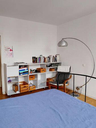 Bedroom corner with bookshelf, armchair, and reading lamp