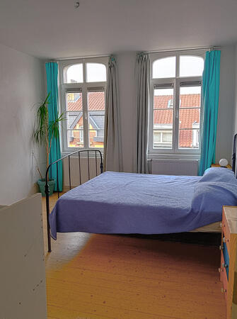 Bright bedroom with large windows and a comfortable double bed